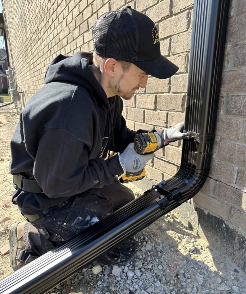 Black 3x4 Downspout being installed with downspout hinge