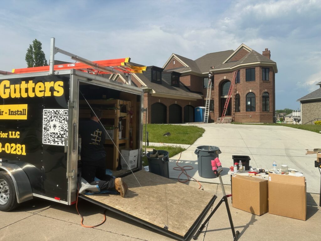 black trailer with yellow writing. large brown brick home in the back