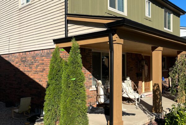 black gutters on a red brick home with green and beige siding