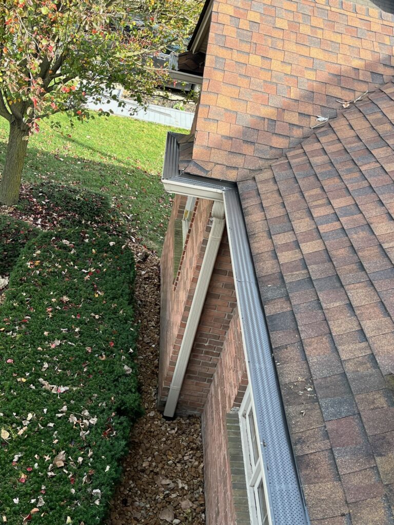 Brown brick home with brown roof and gutter guards