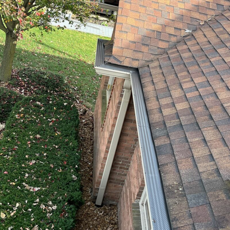 Brown brick home with brown roof and gutter guards