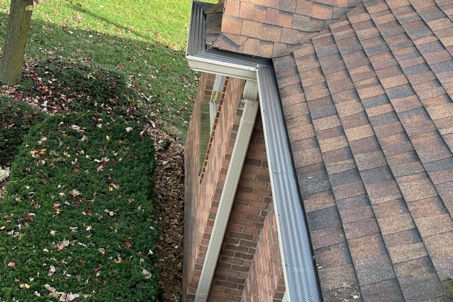 Brown brick home with brown roof and gutter guards