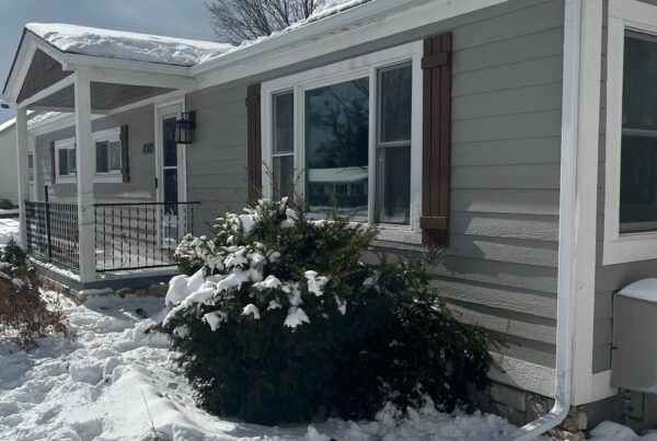 gray siding home with white gutters and snow