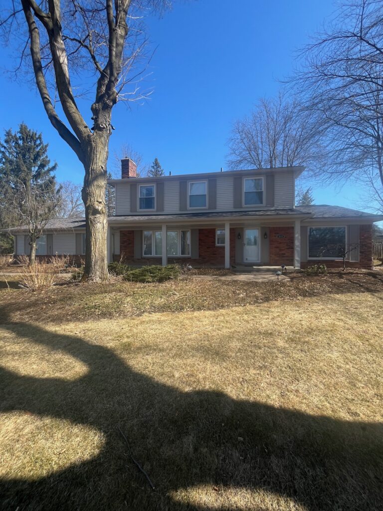 red brick two story home with beige siding