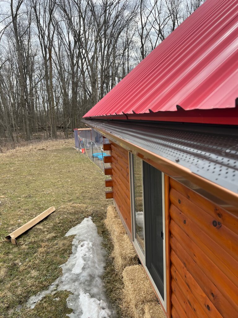 wood log home with a red roof and black gutter guards