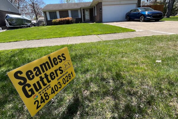 brown brick home with seamless gutter yard sign