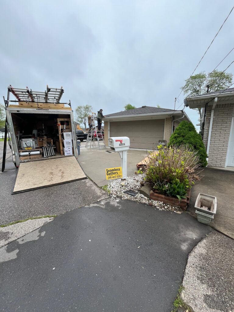 beige brick home with guys working and a J&A Exterior work trailer