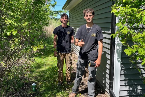 2 men by a downspout on a home