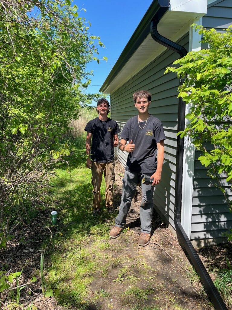 2 men by a downspout on a home