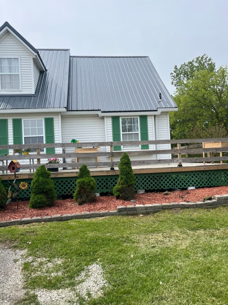 white sided two story home with green shutters and walk around porch