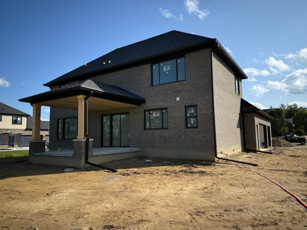 new build, brown brick home with black gutters